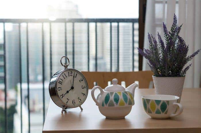 vintage clock on the wood table with tea cup at morning time at Luxury Interior kitchen room