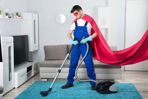 Superhero Janitor Cleaning Carpet With Vacuum Cleaner In Living Room